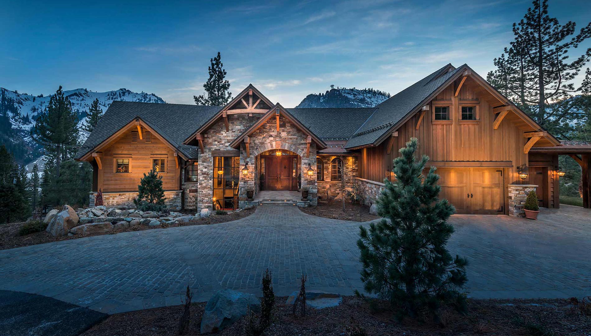 SB-Contstruction-Exterior-Driveway-Entrance Lit up large custom home at night big sky montana