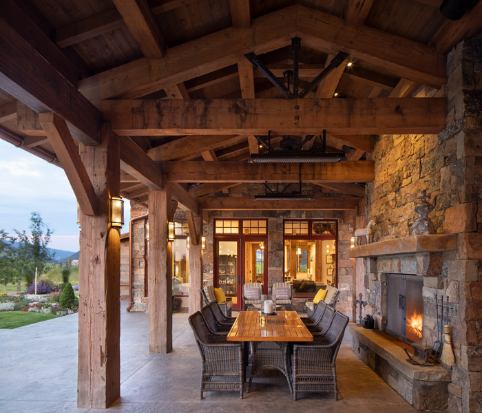 Outdoor roofed dining and seating area by fireplace