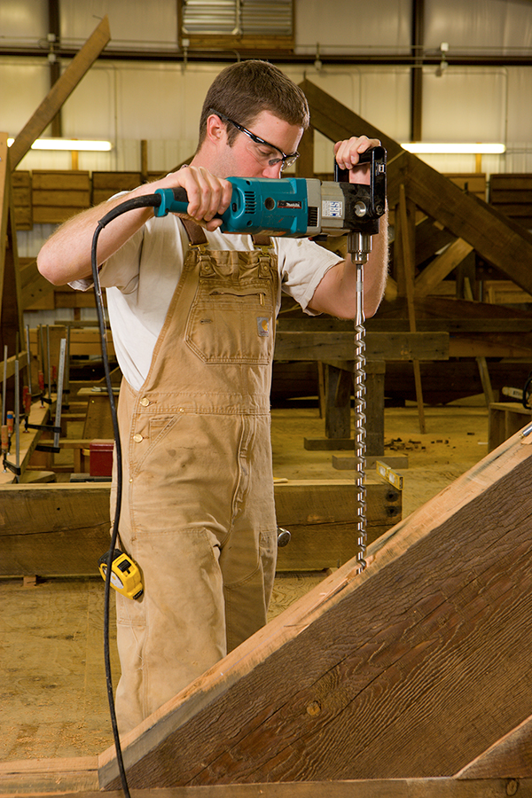 Man drilling into a wood beam